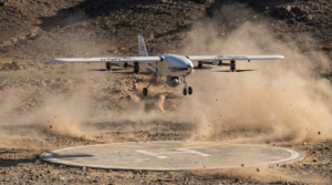 Vertical takeoff and landing fighter aircraft descending onto a confined ground area, showing stable hover, downward thrust, and retractable landing gear.